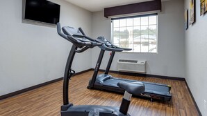 Une salle de sport équipée de deux tapis de course, d’un téléviseur fixé au mur et d’une grande fenêtre donnant sur des immeubles.