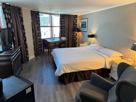Una habitación de hotel con una cama grande, un escritorio con silla, un televisor y una lámpara.