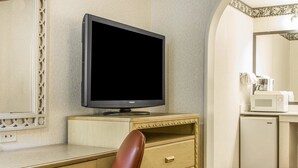 Hotellihuone, jossa on puinen työpöytä, televisio, mikroaaltouuni ja jääkaappi.