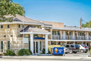 Een Comfort Inn hotel met een beige gevel, een overdekte ingang en een parkeerplaats met meerdere voertuigen.