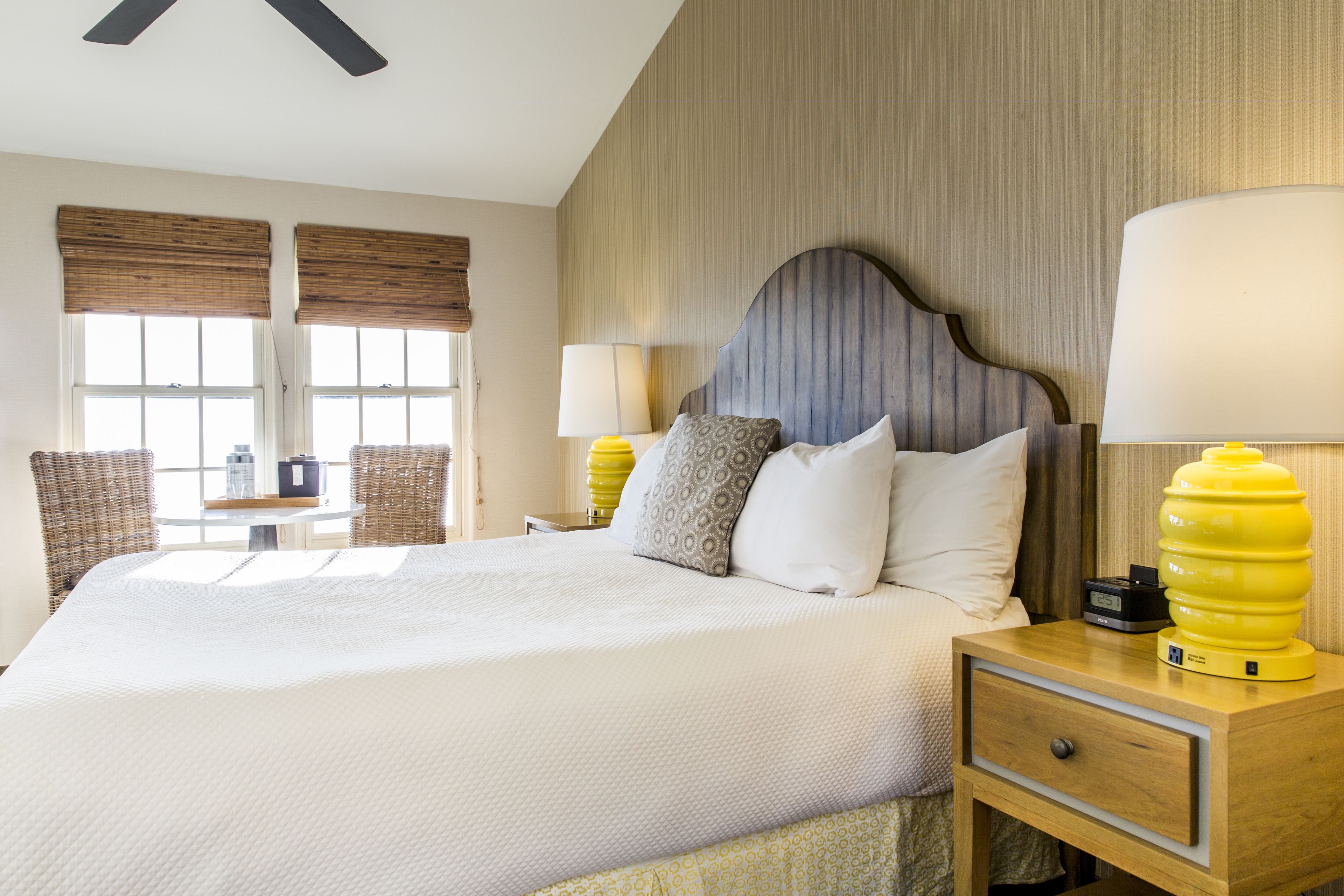 A hotel room with a large bed, two bedside lamps, a wooden nightstand, and a small table with chairs.