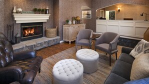 Una sala de estar acogedora con chimenea, sofá de cuero, otomanas y un comedor con una cocina al fondo.