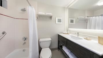 A modern bathroom with a bathtub, toilet, and vanity with a mirror.