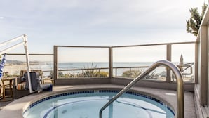 Una piscina en la azotea con vistas claras al océano, rodeada de sillones de descanso y una barandilla.