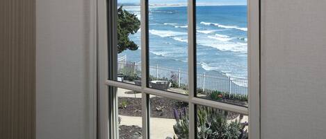 A window with a view of the ocean and a pier.