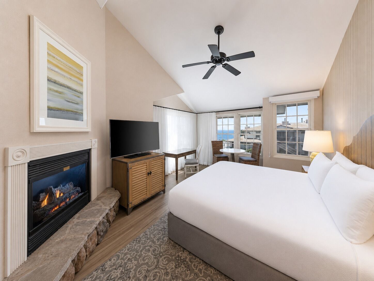 Habitación de hotel con cama, televisor, chimenea, ventilador de techo y vista a la ciudad.