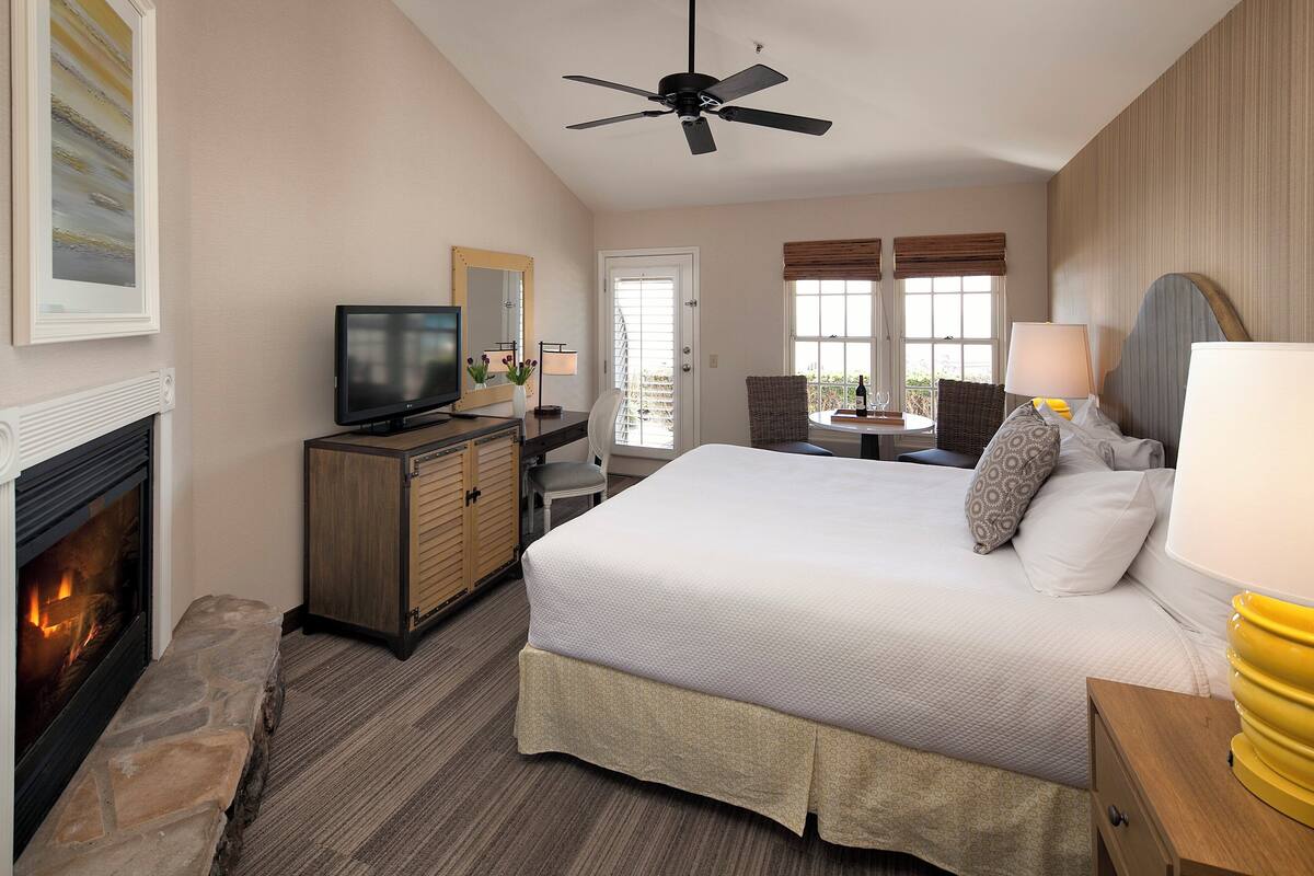 A hotel room with a bed, a television, a fireplace, a desk, and a chair.