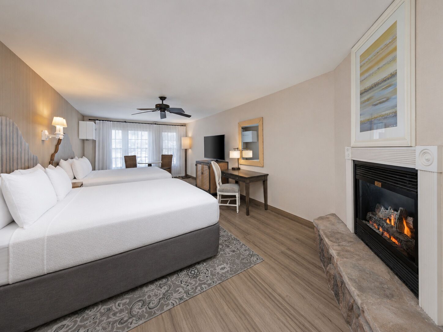 Habitación de hotel con una cama grande, un escritorio, una chimenea y un ventilador de techo.