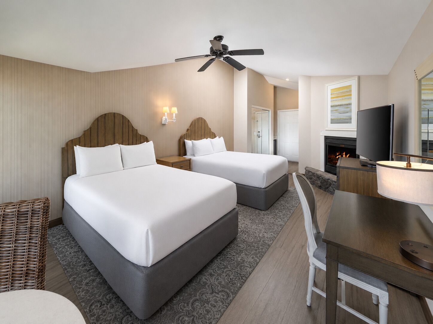 Habitación de hotel con dos camas, ventilador de techo, televisión y chimenea.