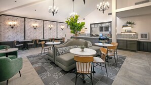 Un comedor moderno con un arreglo central de asientos, una cocina al fondo y un candelabro sobre la mesa.