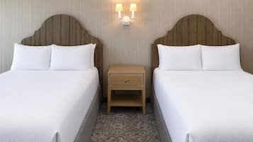 A hotel room with two beds, a nightstand with a lamp, and a patterned carpet.