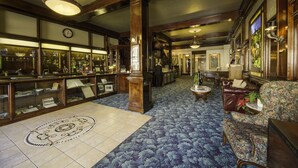 A lobby with a patterned carpet, wooden furniture, and a glass display case. - Historic Cary House Hotel (Placerville)