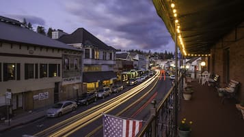 A street view at dusk with illuminated buildings and a long exposure of moving vehicles.