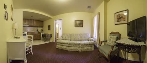 A living room with a sofa, a television, and a dining area with a table and chairs.
