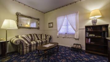 A room with a striped sofa, a small coffee table, a bookshelf, a mirror, and a window with curtains.