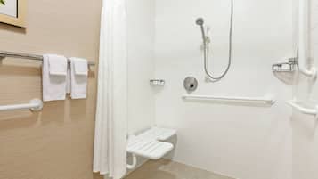 A modern bathroom with white tiles, a shower with a handheld showerhead, a grab bar, and a white towel rack.
