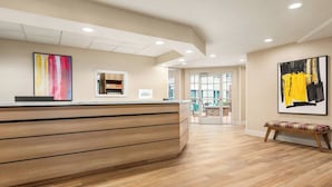A reception area with a wooden reception desk, a bench, and two abstract paintings on the walls.