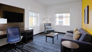 A hotel room with a flat-screen TV, a desk, a chair, a sofa, and two windows. - Holiday Inn Express San Francisco Union Square by IHG (San Francisco)
