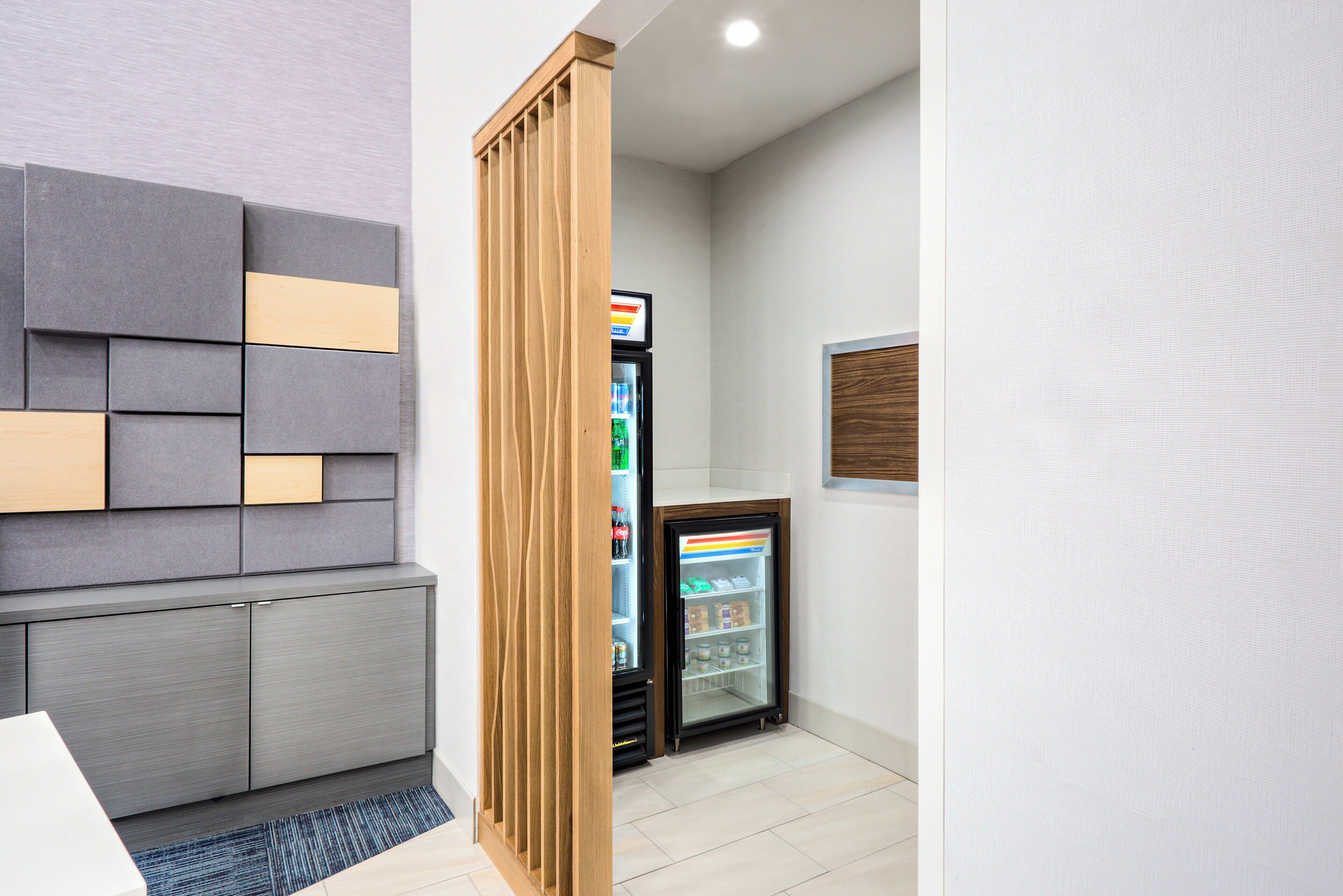A modern room with a grey and wooden accent wall, a small refrigerator, and a whiteboard on the wall.