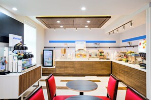 A modern café interior with a self-service counter, seating area, and various food display sections.