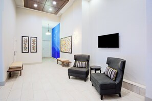 A hallway with seating, artwork, and a television. - Holiday Inn Express San Francisco Union Square by IHG (San Francisco)