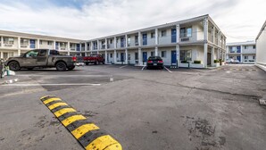 Un motel de varios pisos, un estacionamiento y algunos vehículos estacionados.