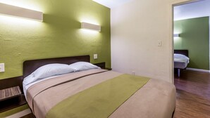 Habitación de hotel con cama, mesita de noche y lámpara fijada a la pared.