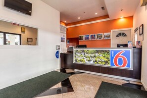 A reception area with a 'No Smoking' sign, a handicap accessible sign, a digital display, and a 'We'll leave the light on for you' sign. - Motel 6 San Rafael, CA (San Rafael)
