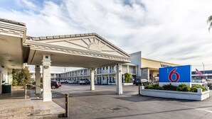 A motel with a gas station, a large '6' sign, and a parking lot with several cars.