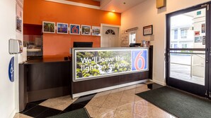 A hotel reception area with a digital display, a reception desk, a wheelchair accessibility sign, and a view of the outside.