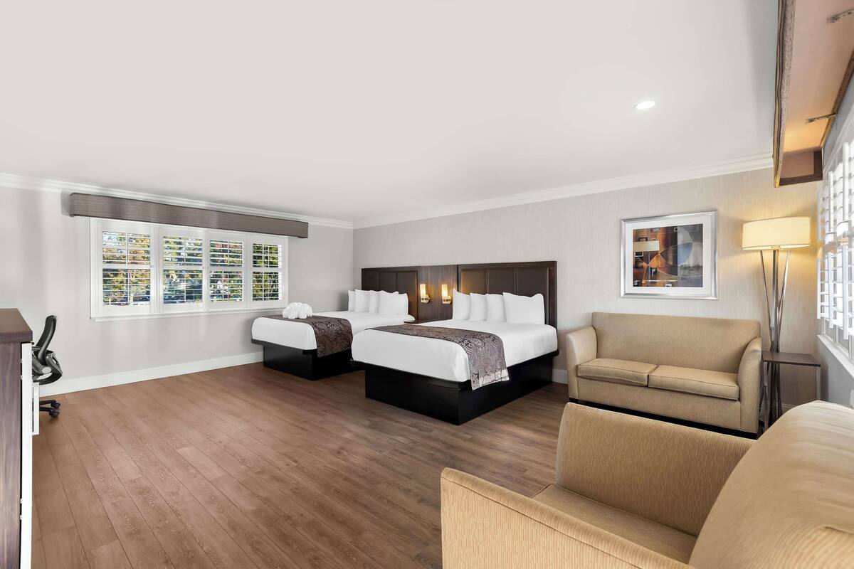 A hotel room with two beds, a sofa, and a desk.