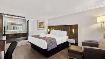 Ein Hotelzimmer mit einem großen Bett, einem Schreibtisch, einem Sessel und einem Nachttisch.