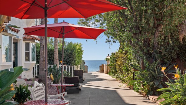 Un sentier bordé de sièges en plein air, de parasols rouges et d’une végétation luxuriante.
