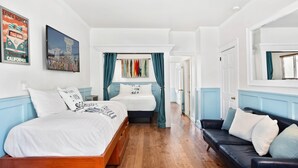 Une pièce avec un lit en bois, un canapé en cuir noir et une fenêtre ornée de rideaux turquoise.