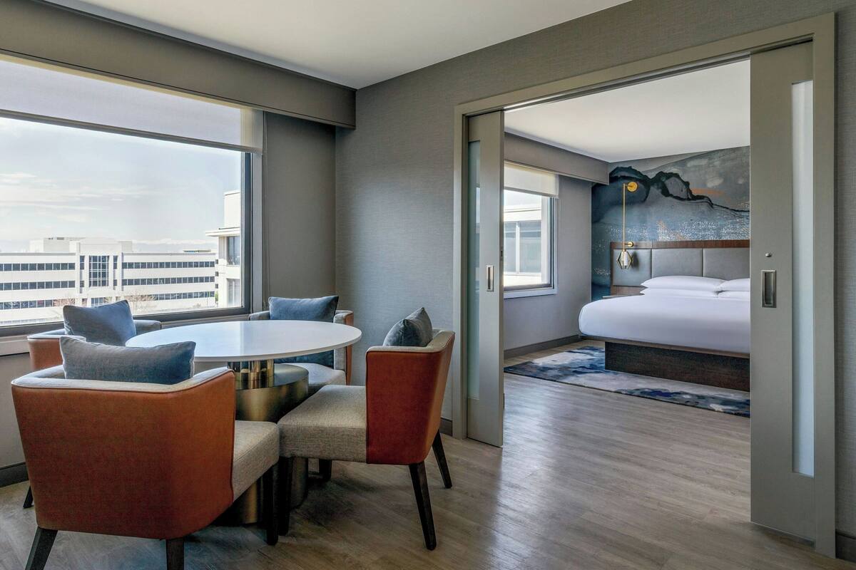 Ett modernt hotellrum med en matplats, en stor säng och utsikt över staden.