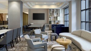 A modern hotel lobby with a seating area, a flat-screen TV, and a bookshelf. - Marriott Denver Airport at Gateway Park (Aurora)