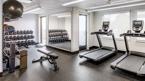 Une salle de sport équipée de tapis de course, d’haltères et de ballons d’exercice.