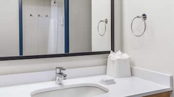A modern bathroom with a white sink, a large mirror, and a towel ring on the wall.
