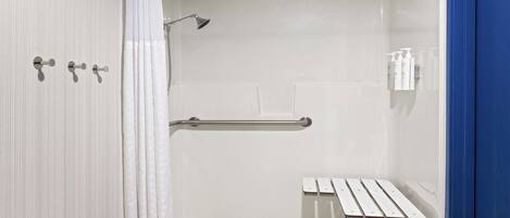 A walk-in shower with a bench, grab bars, and a showerhead.