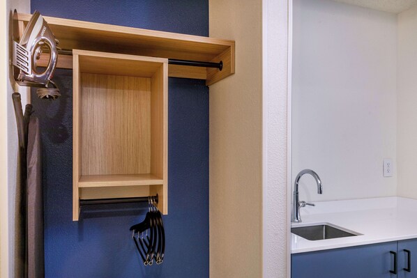 Una cocina con pileta integrada, armarios de madera y un perchero.