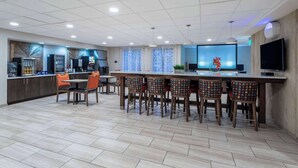 Una cocina moderna con barra, que incluye una isla grande, taburetes de bar y un televisor.
