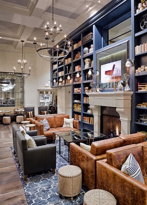 A spacious lounge with leather sofas, a fireplace, and a large bookshelf filled with books and decorative items. - Hotel Teatro (Denver)