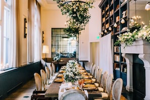 A long dining table with chairs, a chandelier, and bookshelves in the background. - Hotel Teatro (Denver)
