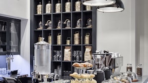 Una cocina moderna con una isla central, un estante negro con frascos de vidrio y una lámpara colgante de estilo industrial.