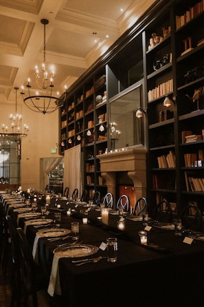 A long dining table set with candles, chairs, and a chandelier. - Hotel Teatro (Denver)