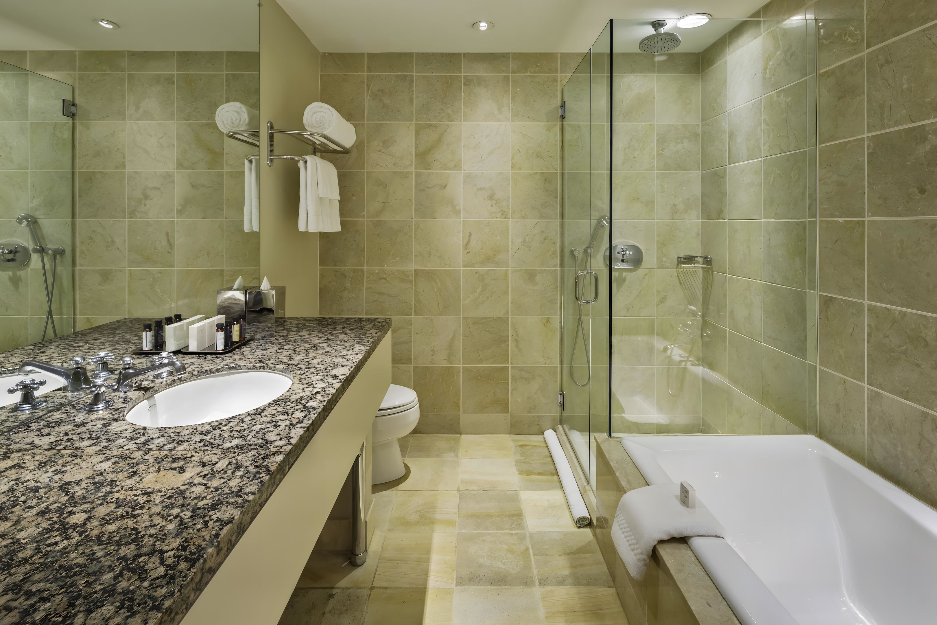 Ein Badezimmer mit einer Granit-Arbeitsfläche, einem weißen Waschbecken, einer Duschkabine und einer weißen Badewanne.