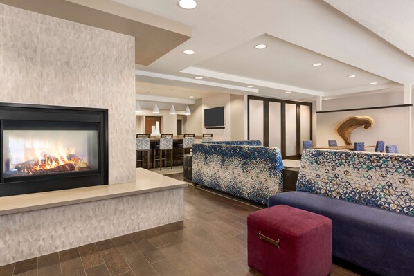 A modern lobby with a fireplace, patterned sofas, and a red ottoman. - Hampton Inn-Denver West/Golden (Golden)