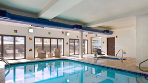 An indoor swimming pool with clear blue water, surrounded by lounge chairs and a view of the outdoors. - Hampton Inn-Denver West/Golden (Golden)