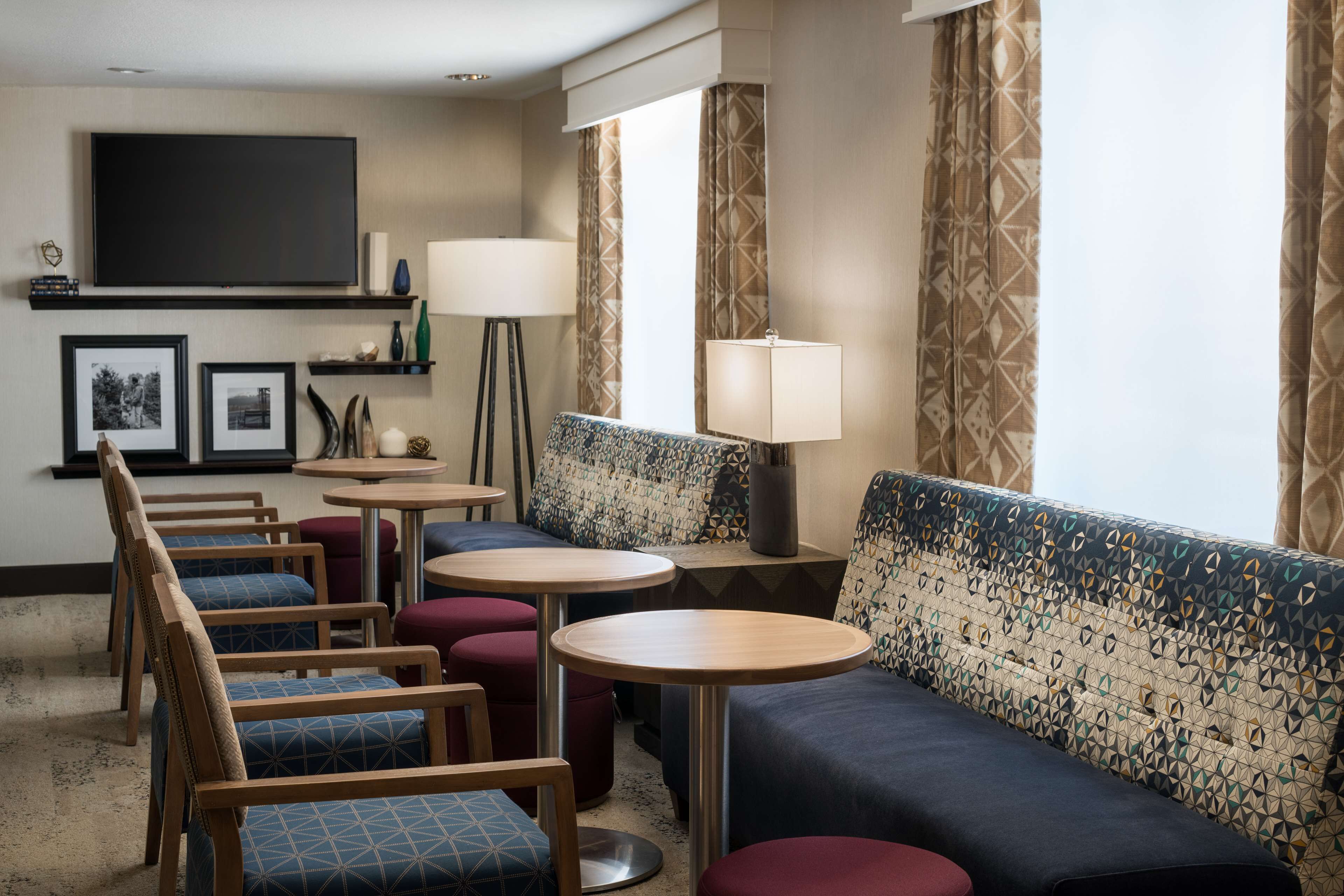 Habitación de hotel con sofá, sillas, televisión y lámpara.