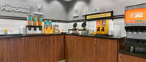 A kitchen area with a coffee machine, waffle maker, and various food containers.